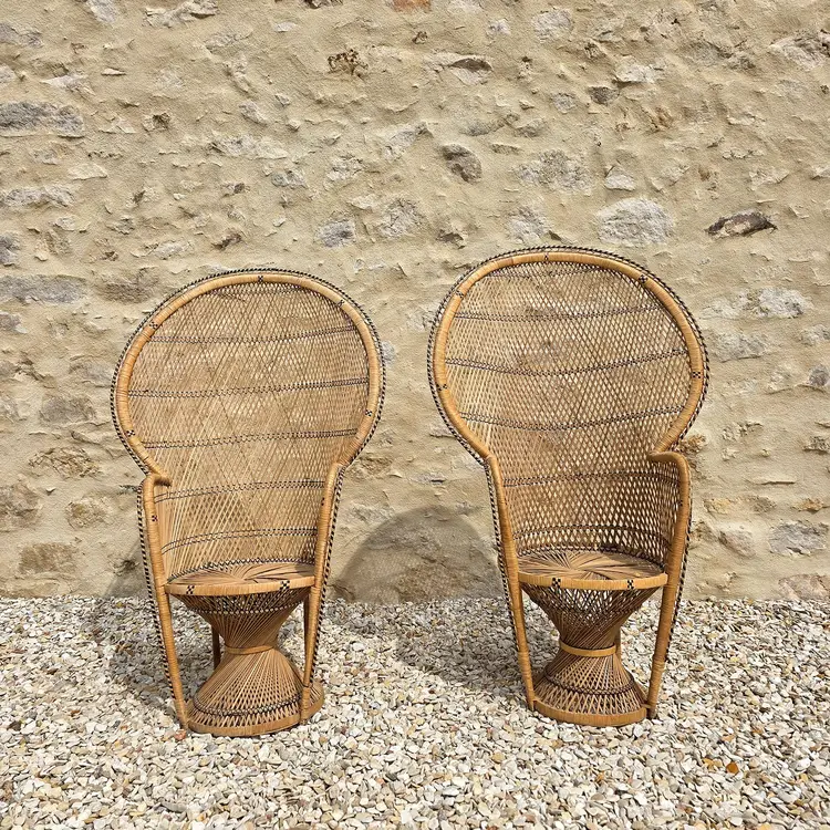 Fauteuils Emmanuelle en rotin devant un mur en pierre